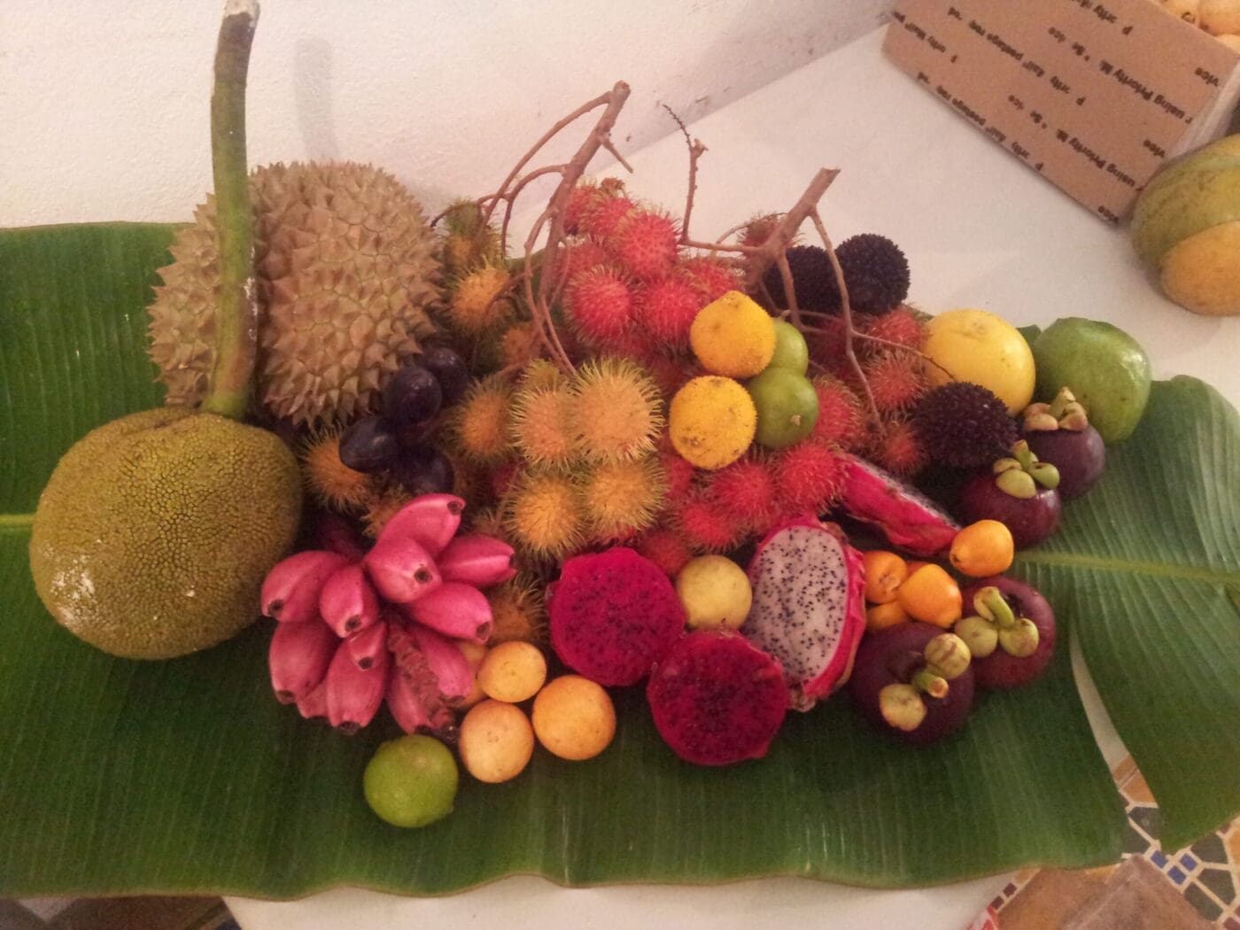 A vibrant assortment of tropical fruits, including durian, rambutan, and mangosteen, arranged on a banana leaf, showcasing the region's diverse produce.